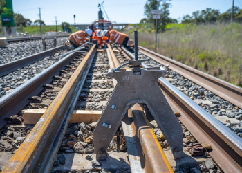 Workers use an a-frame rail aligner, a precision calibration tool.