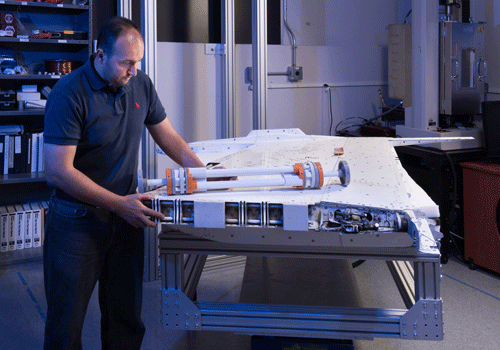 Dr. Othmane Benafan, co-principle investigator for the Spanwise Adaptive Wing Project, inspects a model of the shape memory alloy actuator and the outer wing section from an F/A-18 research plane. Credits: NASA