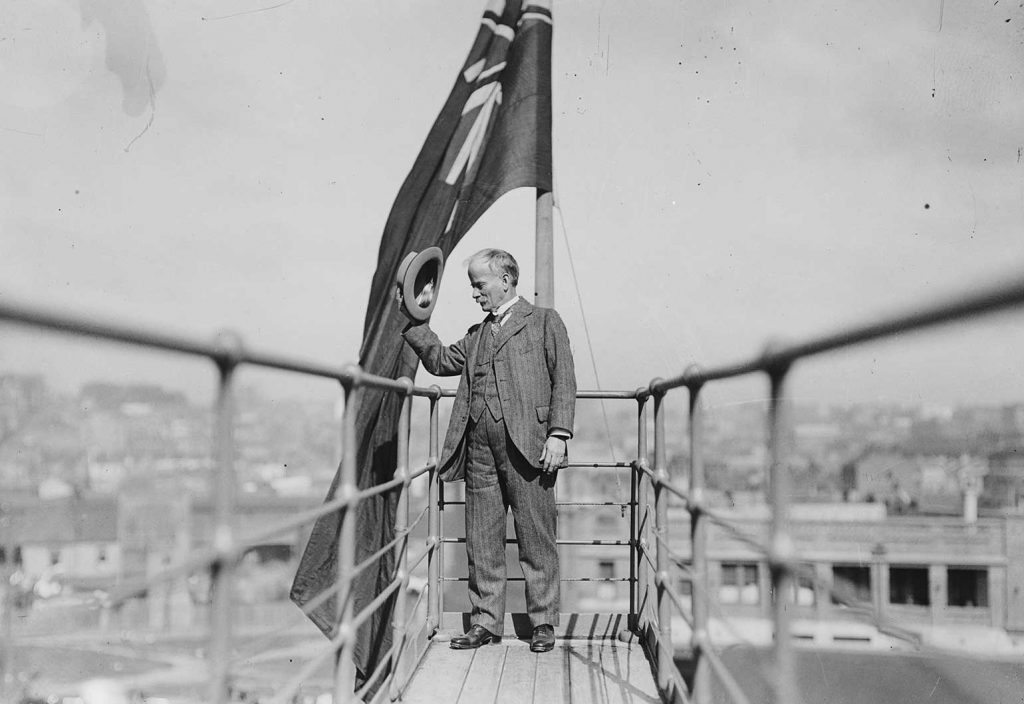 John Bradfield tipping his hat from a walkway on the newly constructed Sydney Harbour Bridge.
