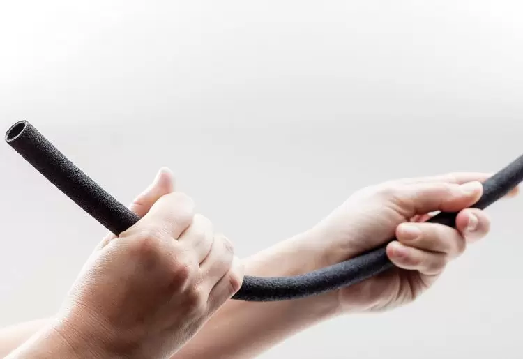 Hands holding a piece of plastic rubber material made by recycling tyres.