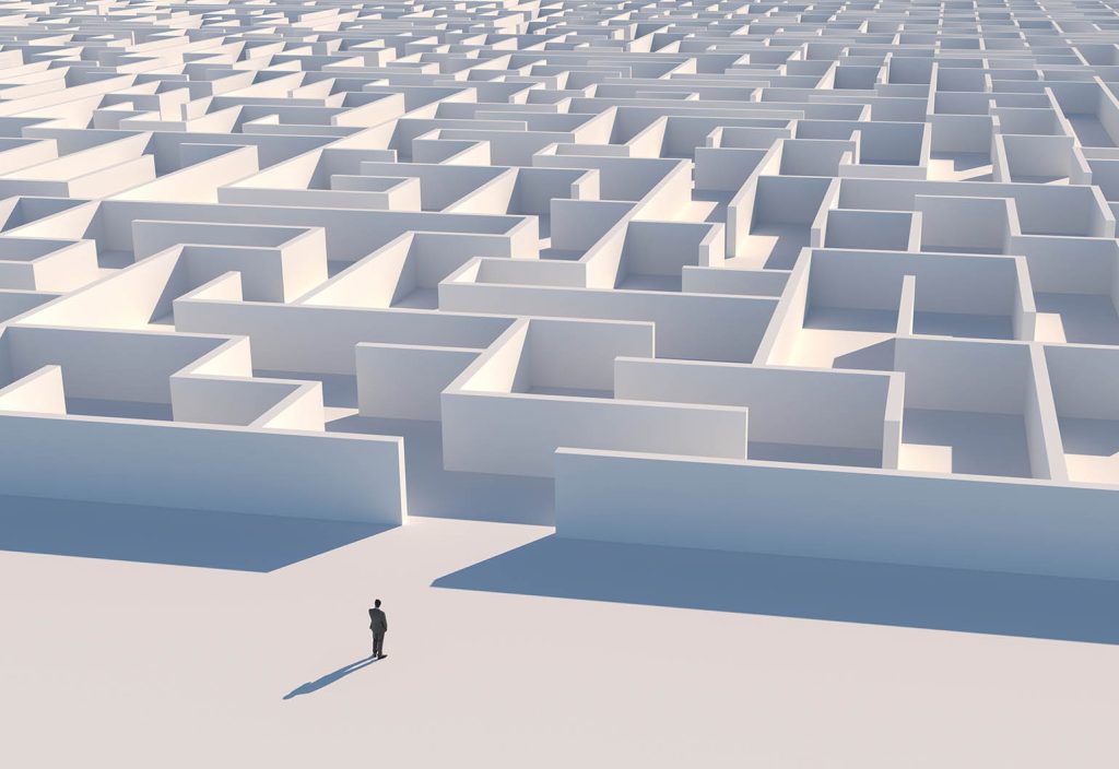 Ethics in engineering - seen from above, a small lone figure stands before an enormous white maze.