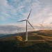 A landscape image of wind turbines with a hilly backdrop