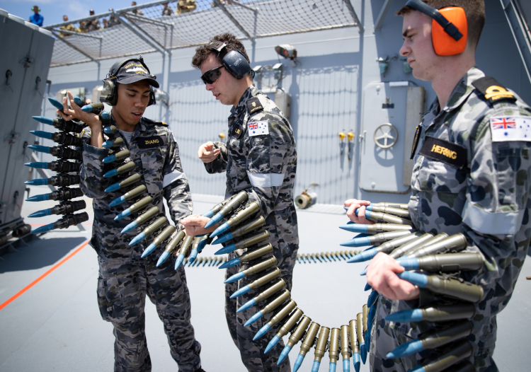 Members from HMAS Canberra’s weapons electrical engineering department prepare to load ammunition into a 25mm typhoon gun. Image credit: Defence Media